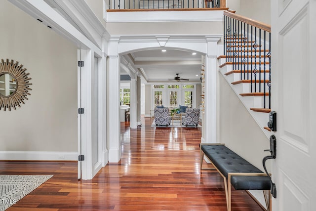 entryway with stairs, crown molding, arched walkways, ceiling fan, and ornate columns