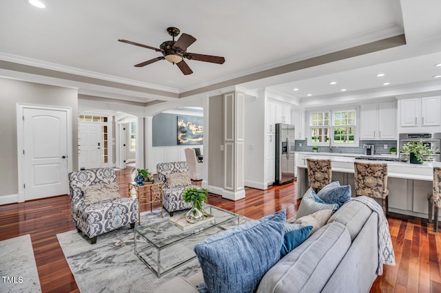 living room with baseboards, ceiling fan, wood finished floors, and crown molding