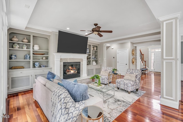 living area with a fireplace, ornamental molding, ceiling fan, and hardwood / wood-style flooring