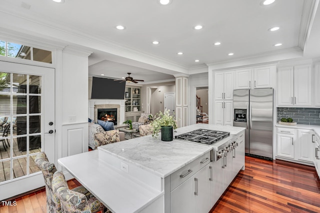 kitchen featuring a glass covered fireplace, stainless steel appliances, crown molding, and a center island