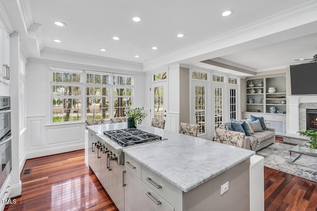 kitchen featuring ornamental molding, stainless steel gas cooktop, a healthy amount of sunlight, and dark wood-type flooring