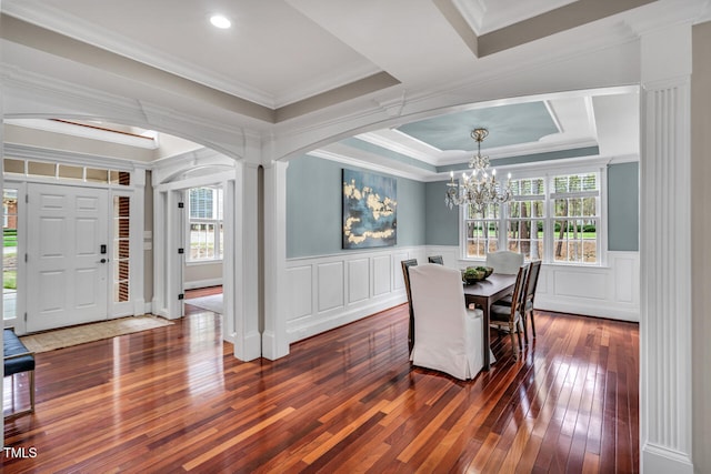 dining room with a tray ceiling, an inviting chandelier, decorative columns, arched walkways, and hardwood / wood-style flooring
