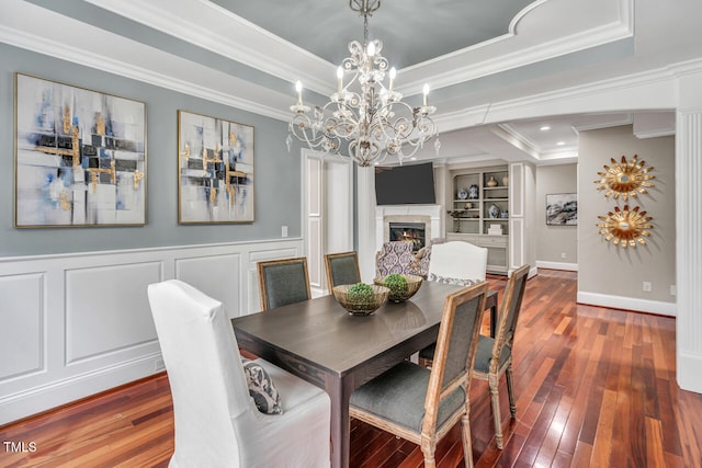 dining space featuring wood-type flooring, a decorative wall, crown molding, and a raised ceiling