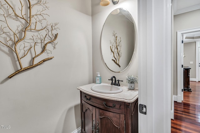 bathroom with baseboards, crown molding, wood finished floors, and vanity