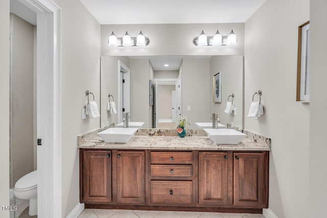 bathroom featuring double vanity, toilet, tile patterned flooring, and a sink