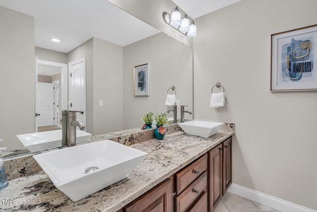 full bath featuring tile patterned floors, double vanity, a sink, and baseboards