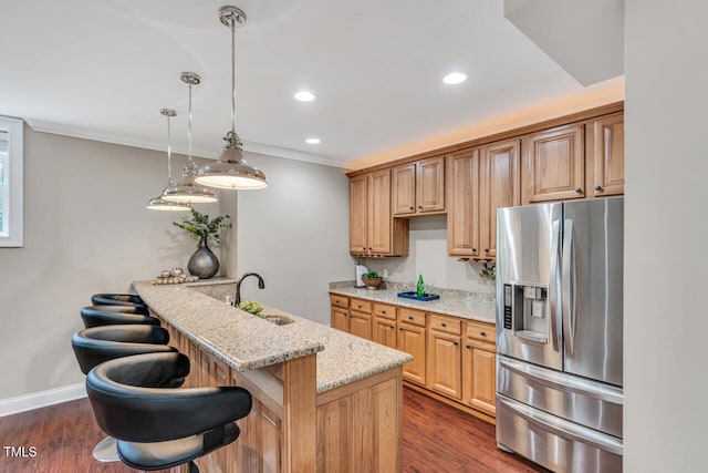 kitchen with crown molding, light stone counters, a kitchen breakfast bar, stainless steel fridge, and dark wood-style flooring