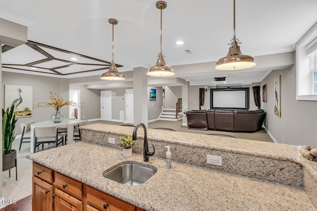 kitchen featuring open floor plan, brown cabinetry, a sink, and light stone counters