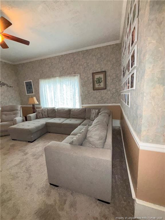 carpeted living area featuring baseboards, wallpapered walls, ornamental molding, and a ceiling fan