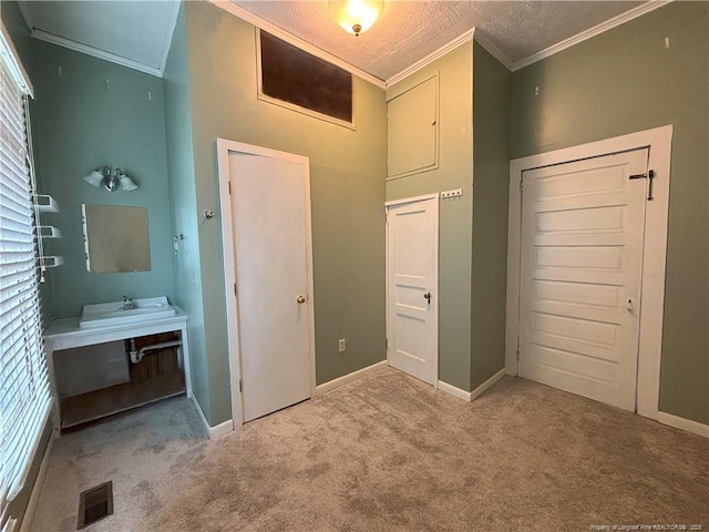 unfurnished bedroom featuring carpet flooring, a textured ceiling, visible vents, baseboards, and ornamental molding