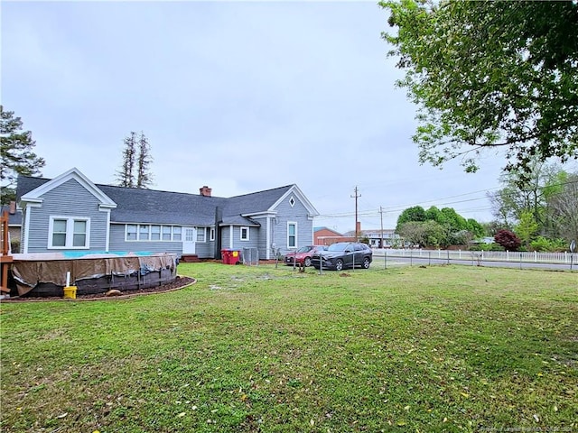 back of house featuring a lawn, a chimney, a fenced in pool, and fence