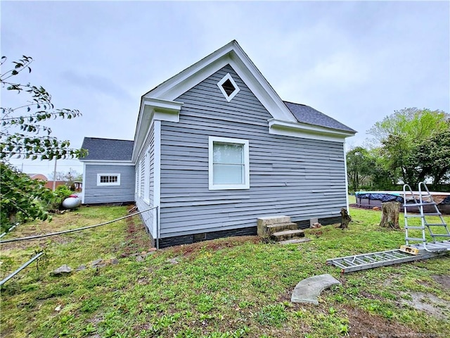 view of side of property featuring roof with shingles and a lawn