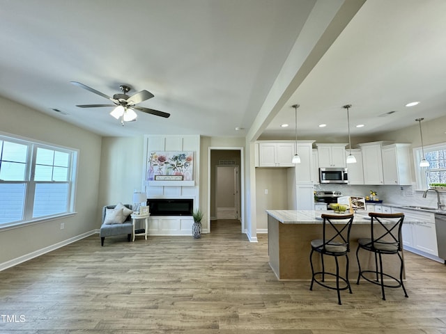 1572 Patterson Rd, Kinston, NC 28504 - kitchen with stainless steel appliances, light wood-type flooring, white cabinets, a sink, and baseboards