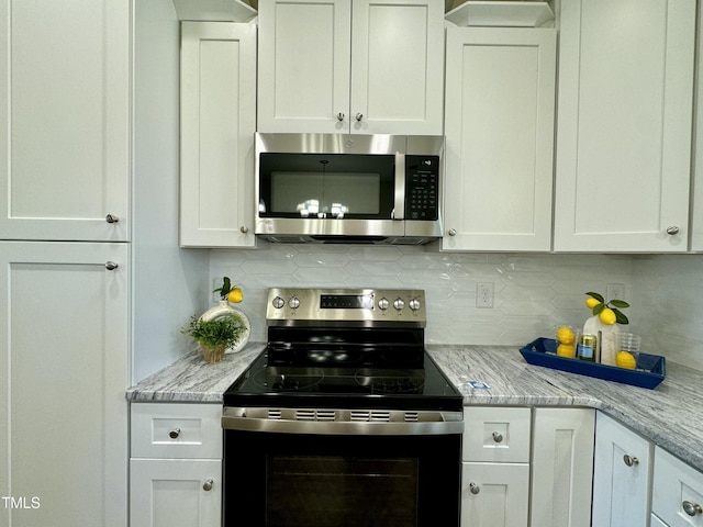 1572 Patterson Rd, Kinston, NC 28504 - kitchen featuring stainless steel microwave, range with electric stovetop, decorative backsplash, white cabinets, and light stone counters