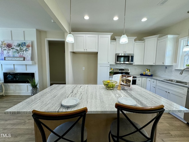 1572 Patterson Rd, Kinston, NC 28504 - kitchen featuring appliances with stainless steel finishes, a sink, white cabinetry, light stone counters, and decorative backsplash