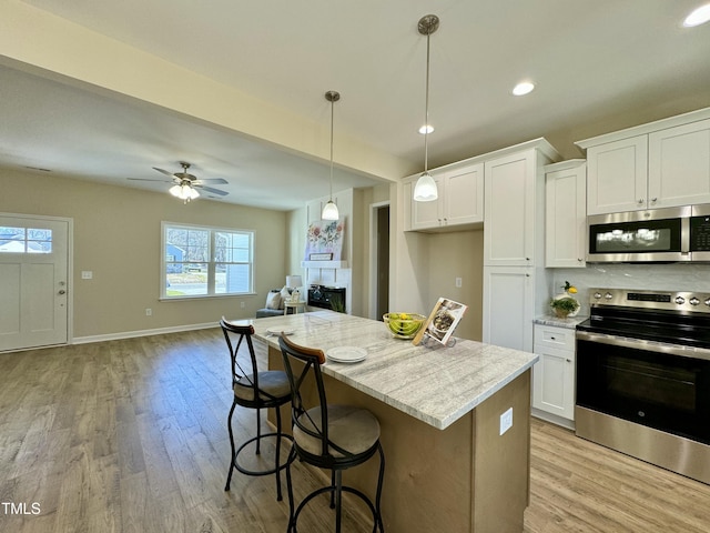 1572 Patterson Rd, Kinston, NC 28504 - kitchen with stainless steel appliances, open floor plan, light wood finished floors, white cabinets, and a kitchen island