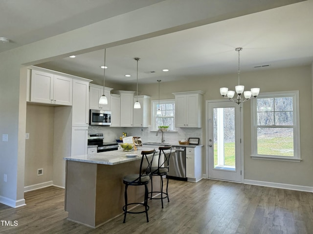 1572 Patterson Rd, Kinston, NC 28504 - kitchen featuring appliances with stainless steel finishes, dark wood-type flooring, white cabinetry, tasteful backsplash, and a center island