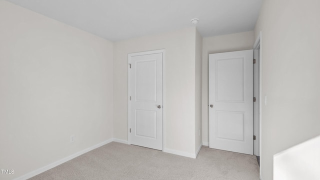 unfurnished bedroom featuring baseboards and light colored carpet