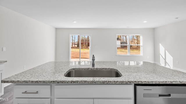 kitchen with white cabinetry, light stone counters, a sink, and dishwasher