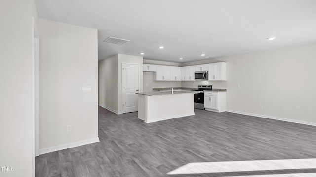 kitchen with white cabinets, wood finished floors, appliances with stainless steel finishes, a sink, and open floor plan