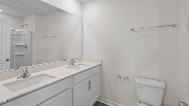 bathroom featuring a shower with door, toilet, double vanity, and a sink