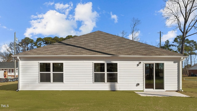 rear view of house featuring a shingled roof and a yard