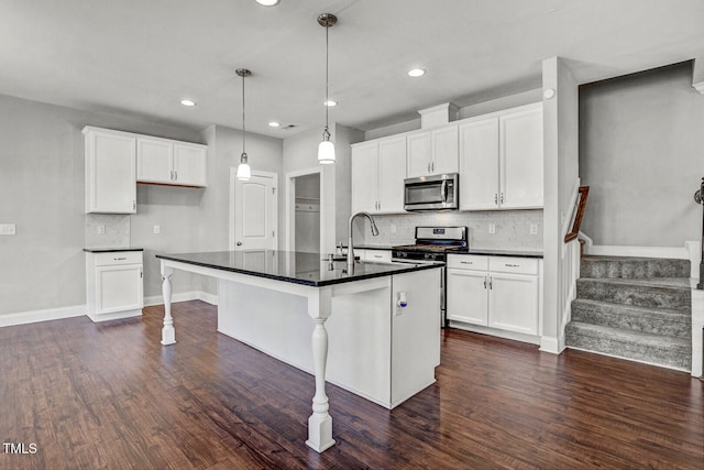 kitchen featuring dark wood-style floors, dark countertops, white cabinets, appliances with stainless steel finishes, and a sink