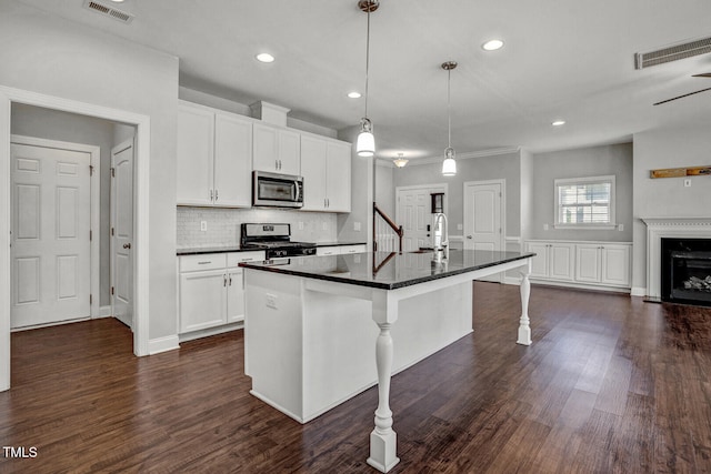kitchen with a kitchen breakfast bar, visible vents, appliances with stainless steel finishes, dark wood-style flooring, and a sink