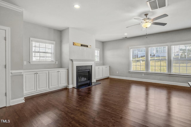 unfurnished living room featuring baseboards, a ceiling fan, dark wood-type flooring, visible vents, and a premium fireplace