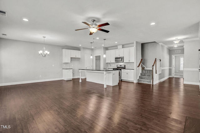 unfurnished living room with dark wood-type flooring, ceiling fan with notable chandelier, recessed lighting, and stairway