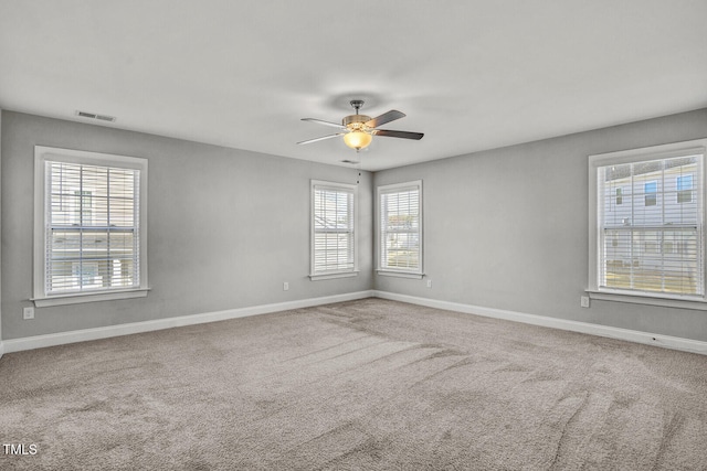 carpeted empty room featuring visible vents, ceiling fan, and baseboards