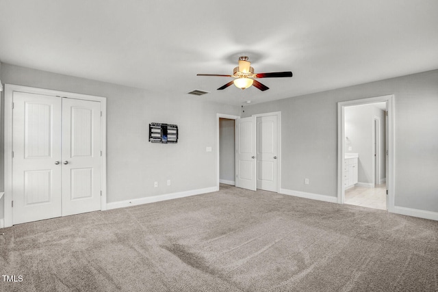 unfurnished bedroom featuring two closets, baseboards, carpet flooring, and ensuite bath