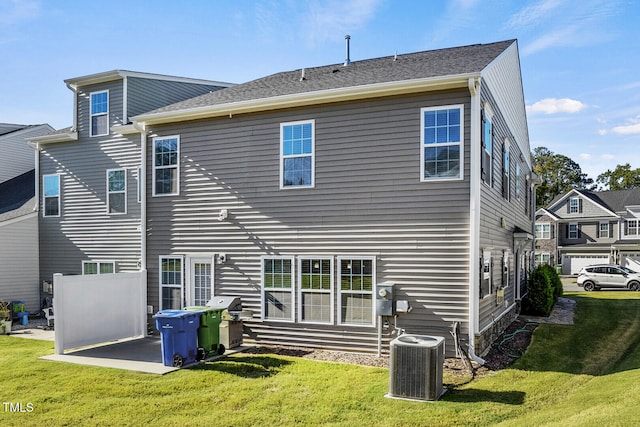 rear view of property with cooling unit and a lawn