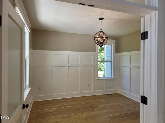 5480 Thom Rd, Mebane, NC 27302 - unfurnished dining area featuring wood finished floors, a decorative wall, a wainscoted wall, and a chandelier