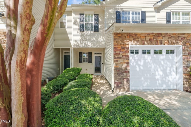 view of front of house featuring stone siding, an attached garage, and concrete driveway