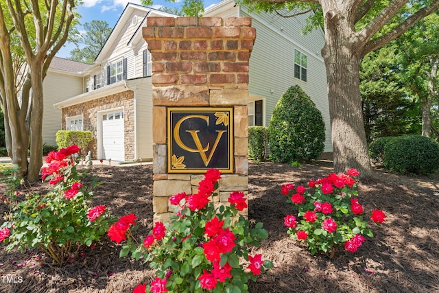 community sign featuring an attached garage