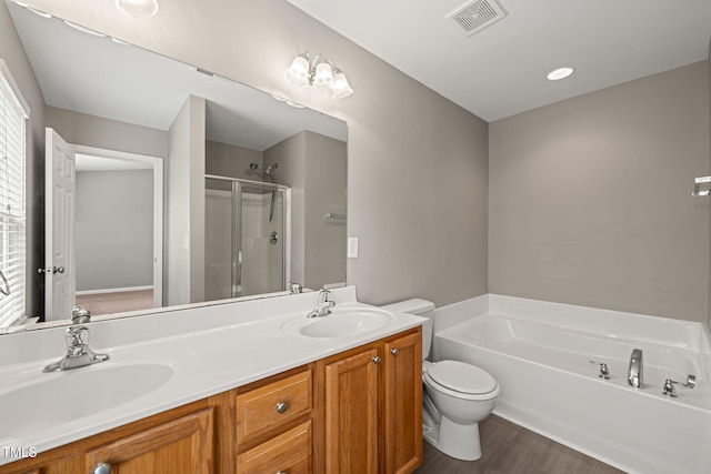 full bathroom featuring a stall shower, a garden tub, double vanity, wood finished floors, and toilet