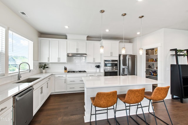 249 Wendover Pkwy, Pittsboro, NC 27312 - kitchen with stainless steel appliances, a sink, under cabinet range hood, a breakfast bar, and tasteful backsplash