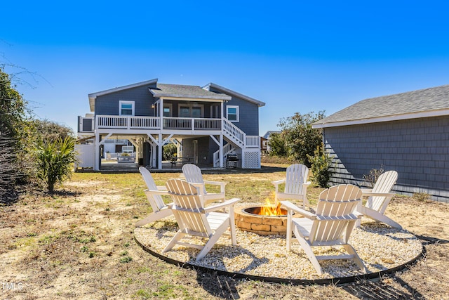 back of property with stairs, a fire pit, a deck, and roof with shingles