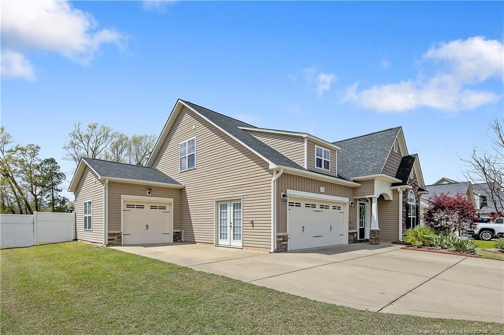532 Saint Johns Loop, Raeford, NC 28376 - view of home's exterior featuring concrete driveway, an attached garage, french doors, stone siding, and roof with shingles