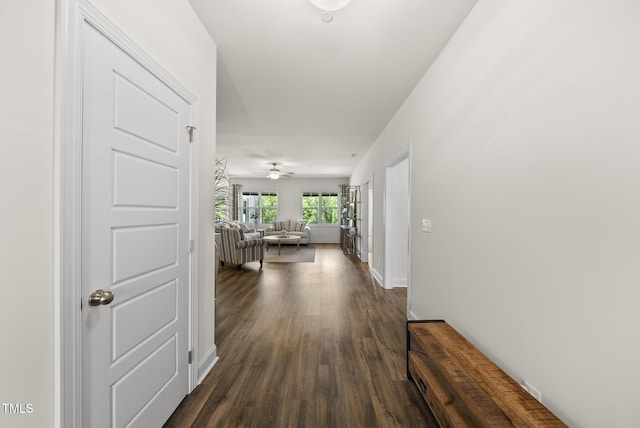 corridor featuring dark wood-style flooring and baseboards