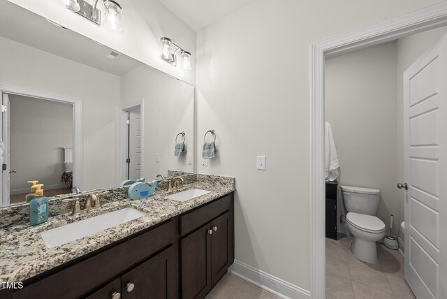 bathroom with double vanity, tile patterned floors, baseboards, and a sink