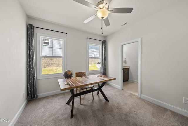 office area featuring ceiling fan, baseboards, visible vents, and light carpet