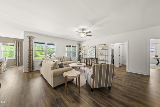 living room with dark wood-type flooring, plenty of natural light, a ceiling fan, and baseboards