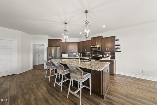 kitchen featuring appliances with stainless steel finishes, an inviting chandelier, dark brown cabinetry, and baseboards
