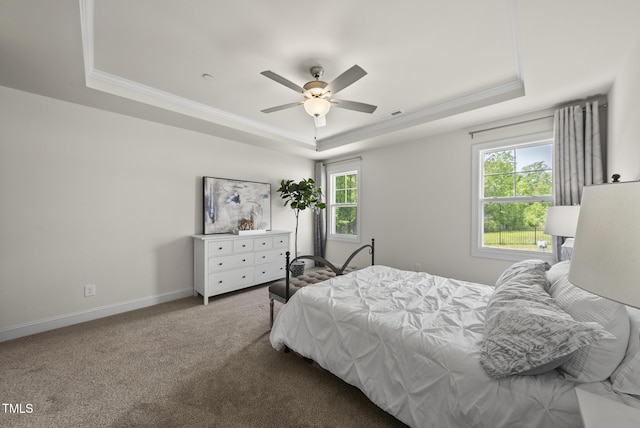 carpeted bedroom featuring ornamental molding, a ceiling fan, baseboards, and a tray ceiling
