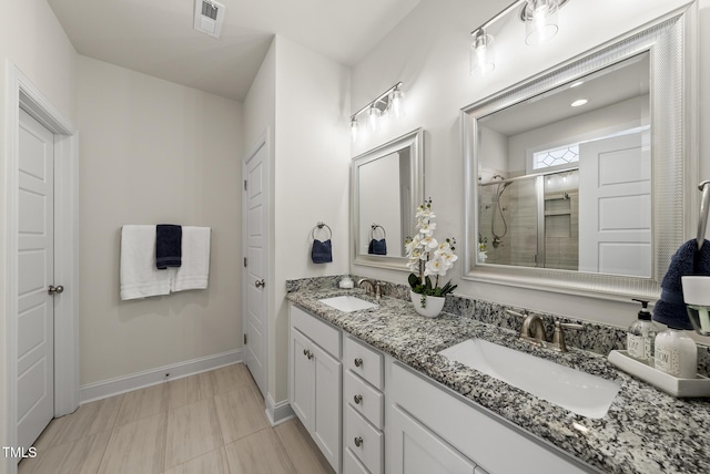 full bath with a stall shower, a sink, baseboards, and visible vents
