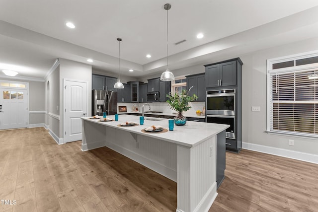 80 Bramble Ln, Clayton, NC 27527 - kitchen with appliances with stainless steel finishes, baseboards, light countertops, light wood-style floors, and a large island with sink