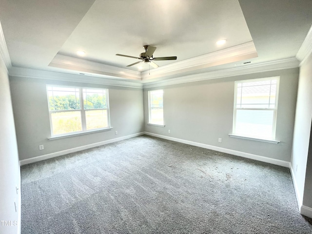 spare room with baseboards, ornamental molding, carpet flooring, a ceiling fan, and a raised ceiling