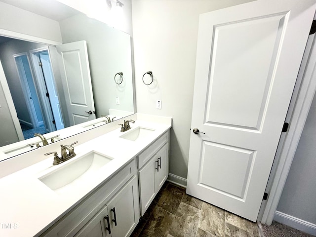 full bathroom with double vanity, a sink, and baseboards